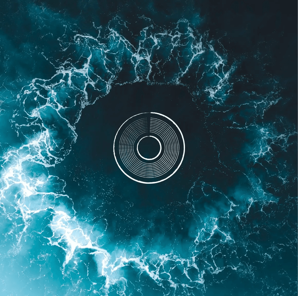 Aerial view of white surf ringing a dark patch of turquoise ocean, around a white concentric-ring emblem